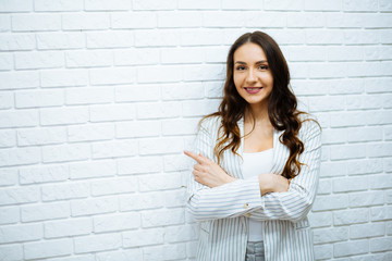 Smiling Asian business woman pointing to the top and looking at camera over white background © ostap_davydiak