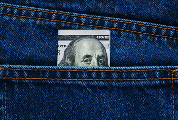 a hundred dollars peeking out from blue jeans pocket