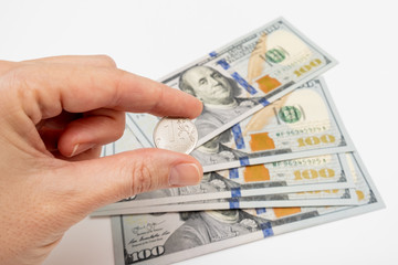 A hand holding one ruble coin and american dollar banknotes on background, ruble devaluation concept