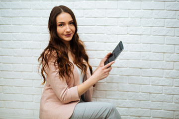 business woman holding tablet on white brick background © ostap_davydiak