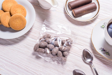 Almonds in chocolate candy in transparent bag, on wooden table