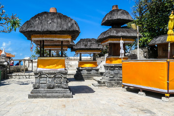 A colorful Hindu Uluwatu Temple, Bali, Indonesia. Main buildings are wrapped with yellow material and ready for the ceremony. Traditional and cultural site. White marble contrasting with blue sky.