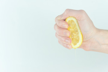 a woman 's hand squeezes a lemon on a white background