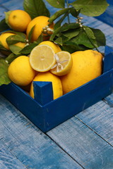 limones con sus hojas recién cogidos del limonero, en caja de fruta azul