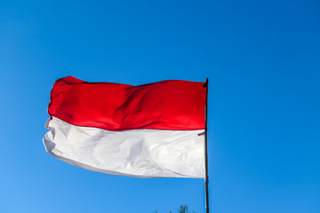 An Indonesian flag waving on the wind on top of Mt Batur, Bali, Indonesia. Red and white colored national flag, swaying gently with the wind.