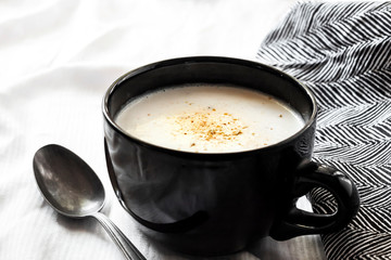 Cauliflower Soup (Creme du Barry) in black bowl on white background with black and white cloth