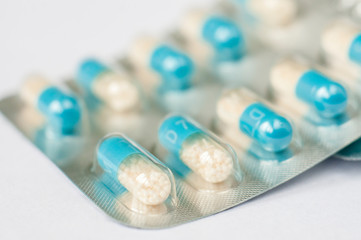 Closeup blue-white antibiotics capsule pills in blister pack. Pharmacy background. Antimicrobial drug resistance. Pharmaceutical industry. Global healthcare.