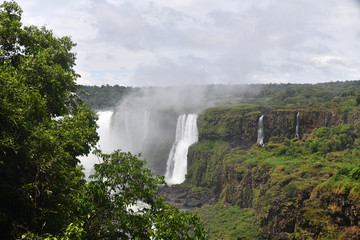 Fototapeta premium Iguazu roaring waterfalls against a jungle and gray sky