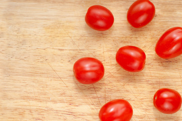 Ripe cherry tomatoes in a wooden cutting board, top view