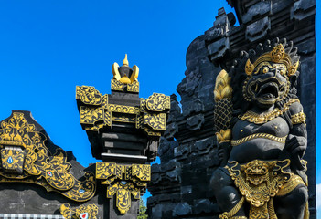 A close up on black and golden entrance gate to Tanah Lot temple on Bali, Indonesia. Traditional Hindu temple. Cultural and historical site. There is a guardian God wearing a golden crown on it.