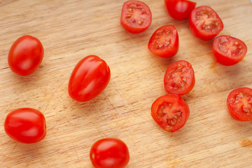 Ripe cherry tomatoes in a wooden cutting board, top view