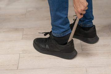 Man putting on shoes with shoehorn