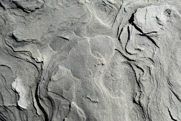 Background texture of stone with smooth streaks, natural surface of sandy soil. Black, white and gray tones.