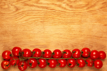 Ripe cherry tomatoes on a wooden board, top view with copy space