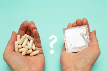 Methods of contraception. Woman holding birth control pills and condom in hand. Birth control pills...