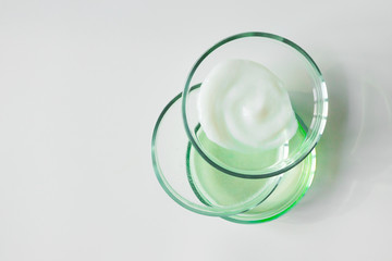 Glass petri dishes with various cosmetic products on white background, copy space. Shampoo, hair...