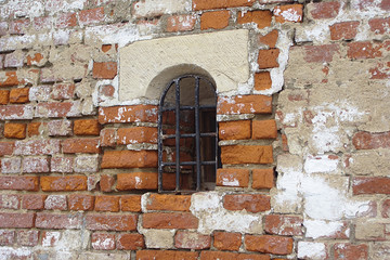 a small window with bars in the monastery wall