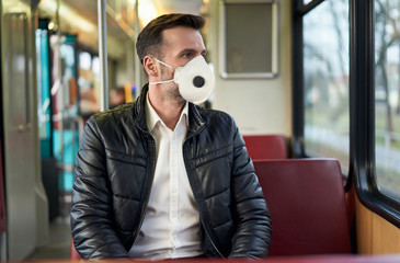 Middle aged man wearing face mask in public transport to protect from coronavirus disease
