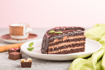 Homemade chocolate cake with milk cream and a cup of coffee on a gray concrete background. side view, selective focus.