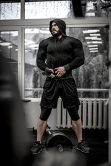 mental and physical growth concept of hard workout training in gym by strong young athlete caucasian man wearing hoodie and powerlifting belt near barbell