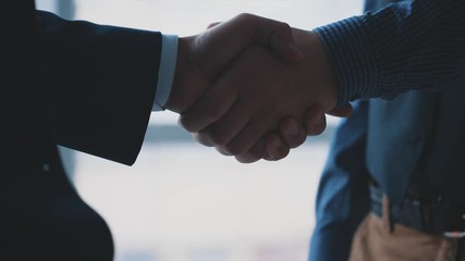 Handshake of two men. Friendly men are shaking hands. Business partners are handshaking. Blurred background. Close up. Slow motion. Slowmo. 4K.