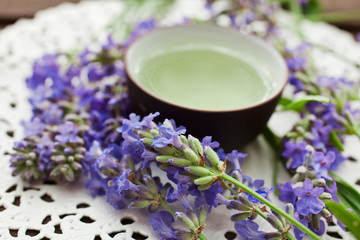 Lavender tea in clay cup with lavender flowers on a paper napkin.