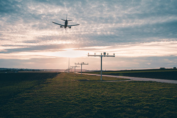 Low-angle view of passenger airplane approaching STR Airport Stuttgart at sunset
