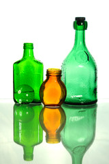 Empty bottles on a white background three pieces green and orange wet with drops on a white background vertical reflection isolate 