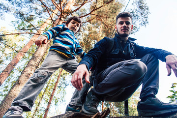 little son with father climbing on tree together in forest, lifestyle people concept, happy smiling family on summer vacations