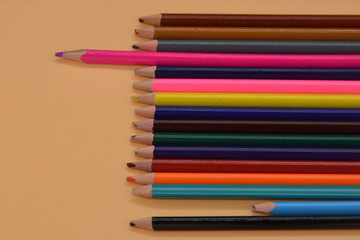 a pink pencil in front of a crowd of multicolored pencils. Minimal creative concept. Leadership, independence, think differently, business success concept