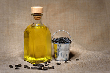 Bucket with seeds and a bottle of sunflower oil on a brown background. Farm.
