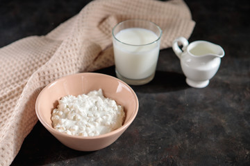 Cottage cheese with a glass of milk on the table, space for text. Fresh dairy products on a dark background.