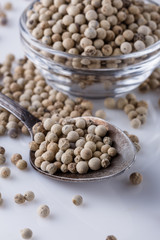 white peppercorns in glass bowl with spoon