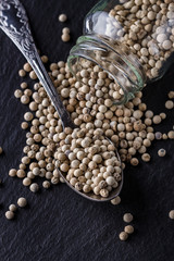 white peppercorns on dark slate stone background