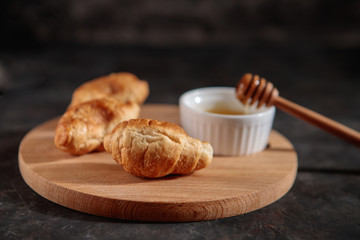 Croissants with honey on the table, close-up, on a dark background. Fresh bakery.