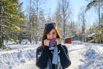 Fototapeta na wymiar An European woman smiling and enjoying sunny winter weather outdoor wearing a scarf and a sunglass as a fashion statement