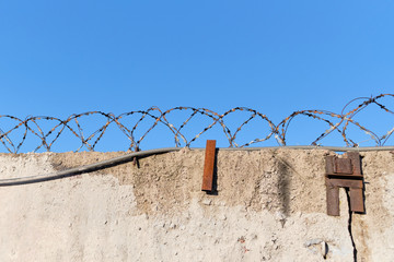 Barbed wire prison wall with blue sky background. © gesrey