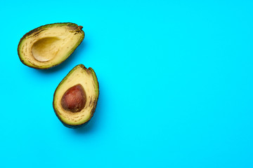 A rotten avocado cut in half on blue background.