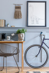 Stylish scandinavian living room with mokc up poster frame on the shelf, wooden desk, chair, bicycle, office supplies and personal accessories in design home decor.