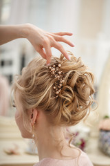Makeup artist, hair professional stylist makes young beautiful bride bridal makeup before wedding in a morning