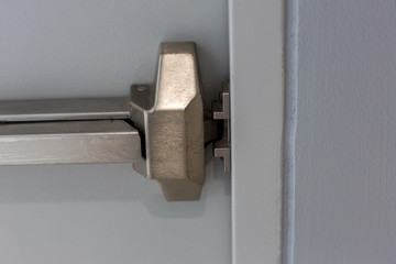 Emergency fire exit door. Closed up latch and rusty door handle of emergency exit. Push bar and...