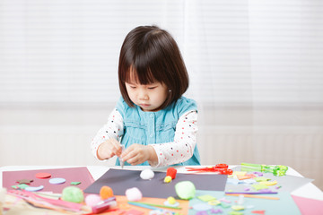 toddler girl learn making  Origami at home against white background