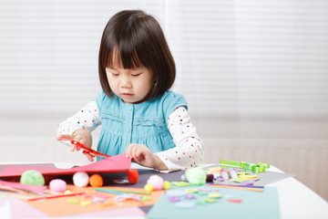 toddler girl learn making  Origami at home against white background