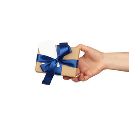 hand hold a wrapped gift in brown craft paper with tied silk blue bows, subject is isolated on a white background