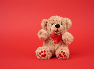 cute little brown teddy bear, toy is sitting on a red background