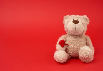 cute little brown teddy bear, toy is sitting on a red background