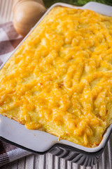 Delicious potato casserole with meat and cheese on a white wooden background