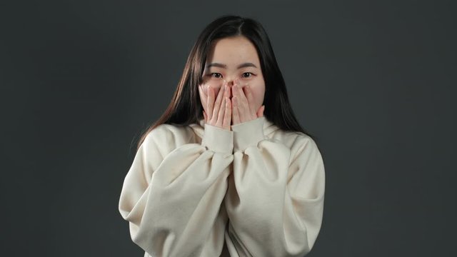 Young frightened asian woman shocked isolated over grey background. Stressed and depressed woman because of bad news