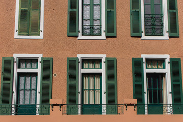 Windows with green wooden shutters. Facade of old building. Traditional ancient architecture in Europe. Vintage exterior of house. 