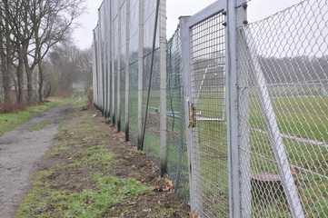 Großer veralteter Zaun mit Fußballfeld im Hintergrund